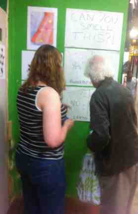 Jo Galloway at Leeds Market helps a man to sample smells a smell and record with a sticker